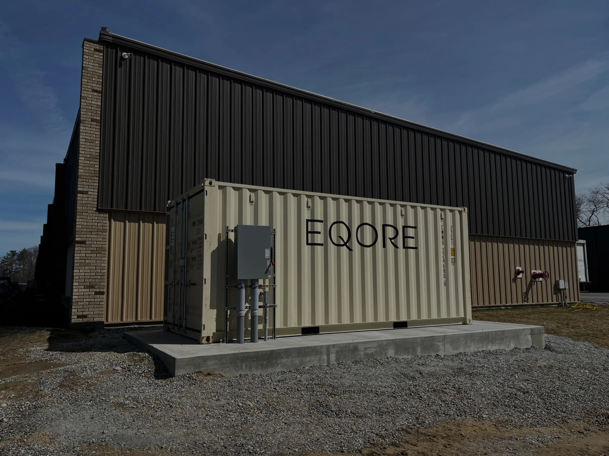 An EQORE battery container on a concrete pad beside the Aalberts industrial facility